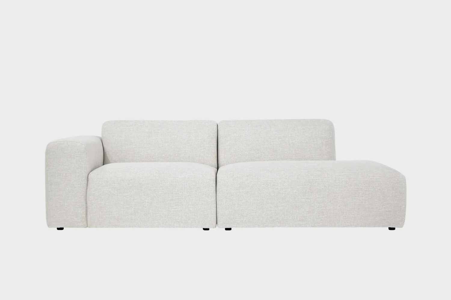 BOHO-avodivaani-do-257x107cm-Sacco02-Finsoffat Boho-avodivaanisohva valkoisella kankaalla verhoiltuna, käsinoja vasemmalla ja divaaniosuus oikealla vaaleaa taustaa vasten.