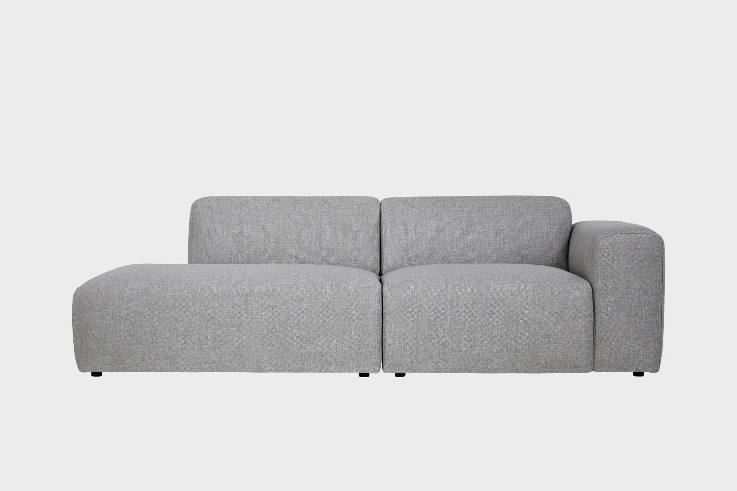Boho-avodivaanisohva harmaalla kankaalla verhoiltuna, käsinoja oikealla ja divaaniosuus vasemmalla vaaleaa taustaa vasten.