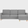 Harmaa divaanivuodesohva, jossa divaani edestäpäin katsottuna oikealla ja tammen värisillä jaloilla kuvattuna vaalean harmaata taustaa vasten.