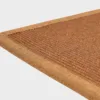 Kuparin värinen VM Carpet Esmeralda matto. Lähikuva maton kulmasta, josta näkyy kanttaus ja maton materiaali.