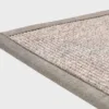 Harmaa VM Carpet Esmeralda matto. Lähikuva maton kulmasta, josta näkyy kanttaus ja maton materiaali.