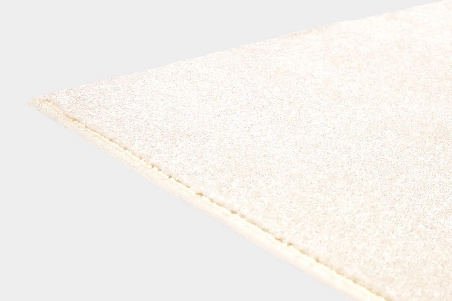Valkoinen VM Carpet Hattara matto. Lähikuva maton kulmasta, josta näkyy kanttaus ja maton materiaali.
