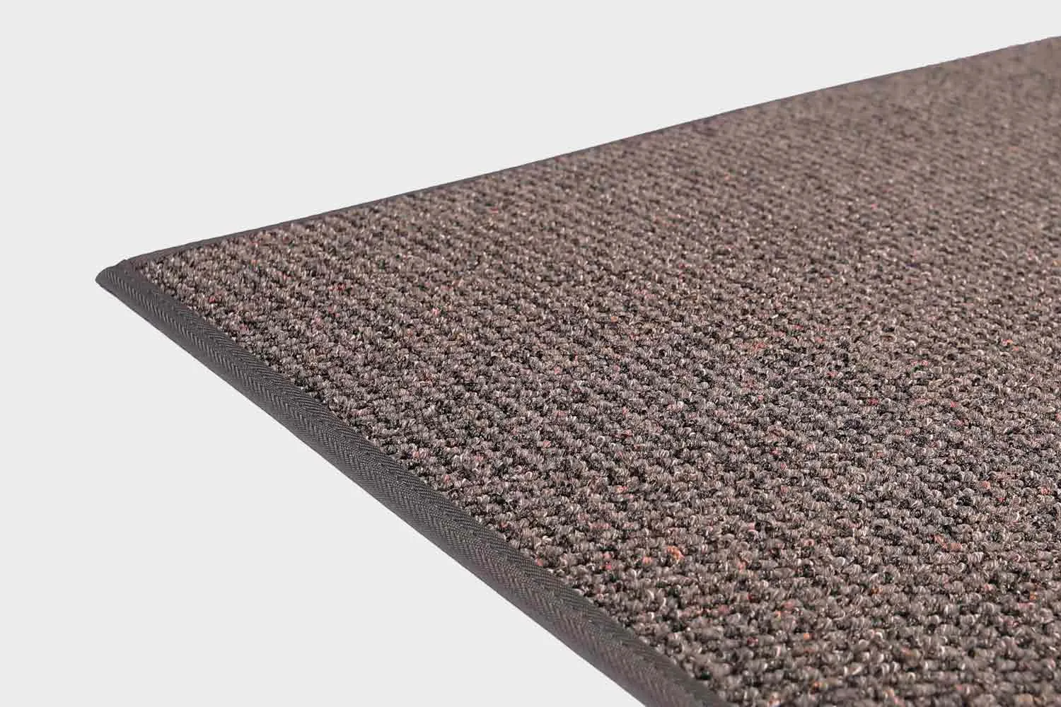 VM-Carpet-Tweed-197-tummanharmaa Tummanharmaa VM Carpet Tweed matto. Lähikuva maton kulmasta, josta näkyy kanttaus ja maton materiaali.