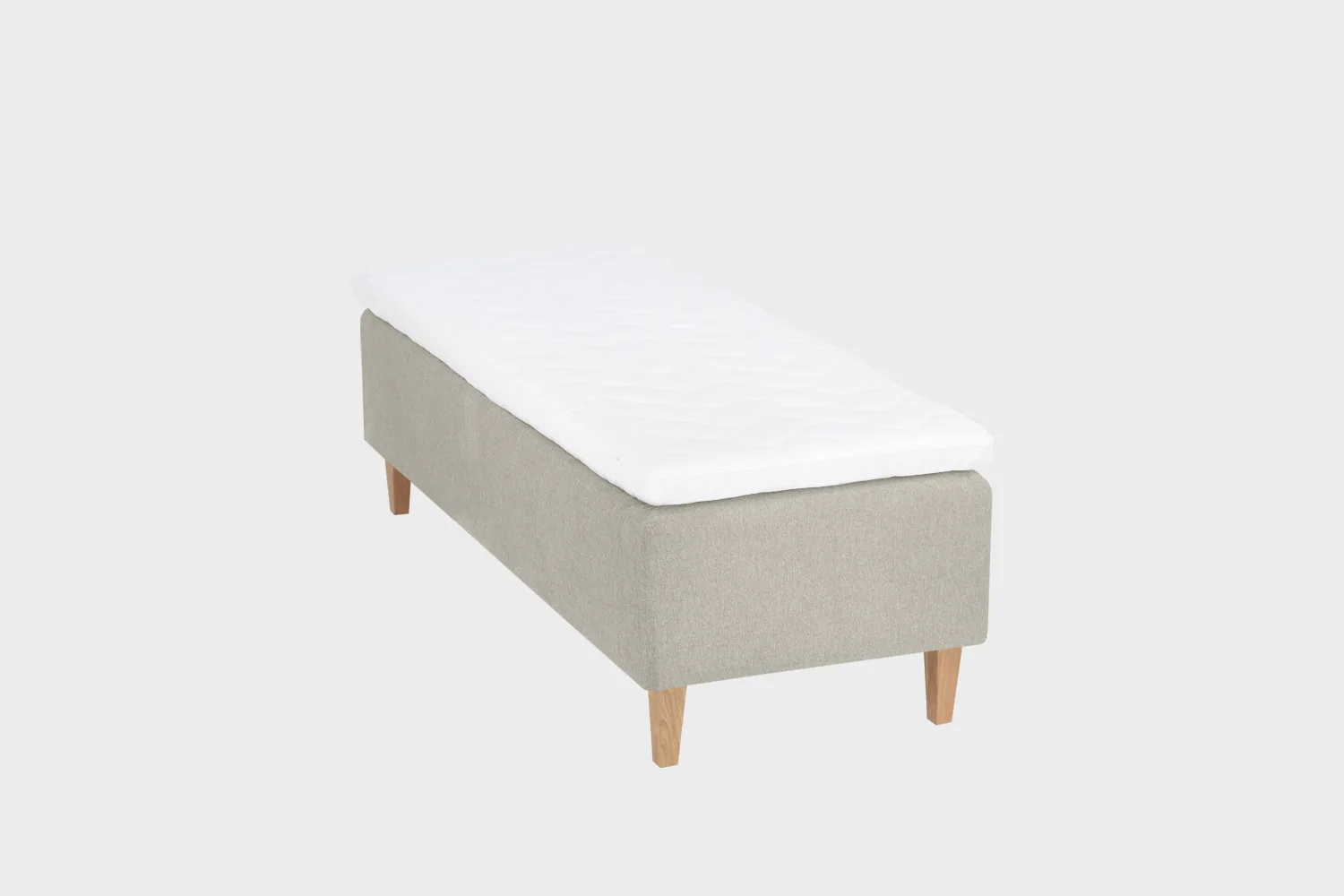 Vaalean beige 80 cm leveä ja 200 cm pitkä runkopatja, jossa on tammen väriset kantikkaat puujalat ja valkoinen petauspatja.