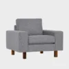 studio-xl-lepotuoli-100x90-das51grey-pahkina-finsoffat Harmaa kangasverhoiltu nojatuoli pähkinän värisillä jaloilla. Tuolissa on leveät käsinojat ja se on asetettu viistosti vaalean harmaata taustaa vasten.