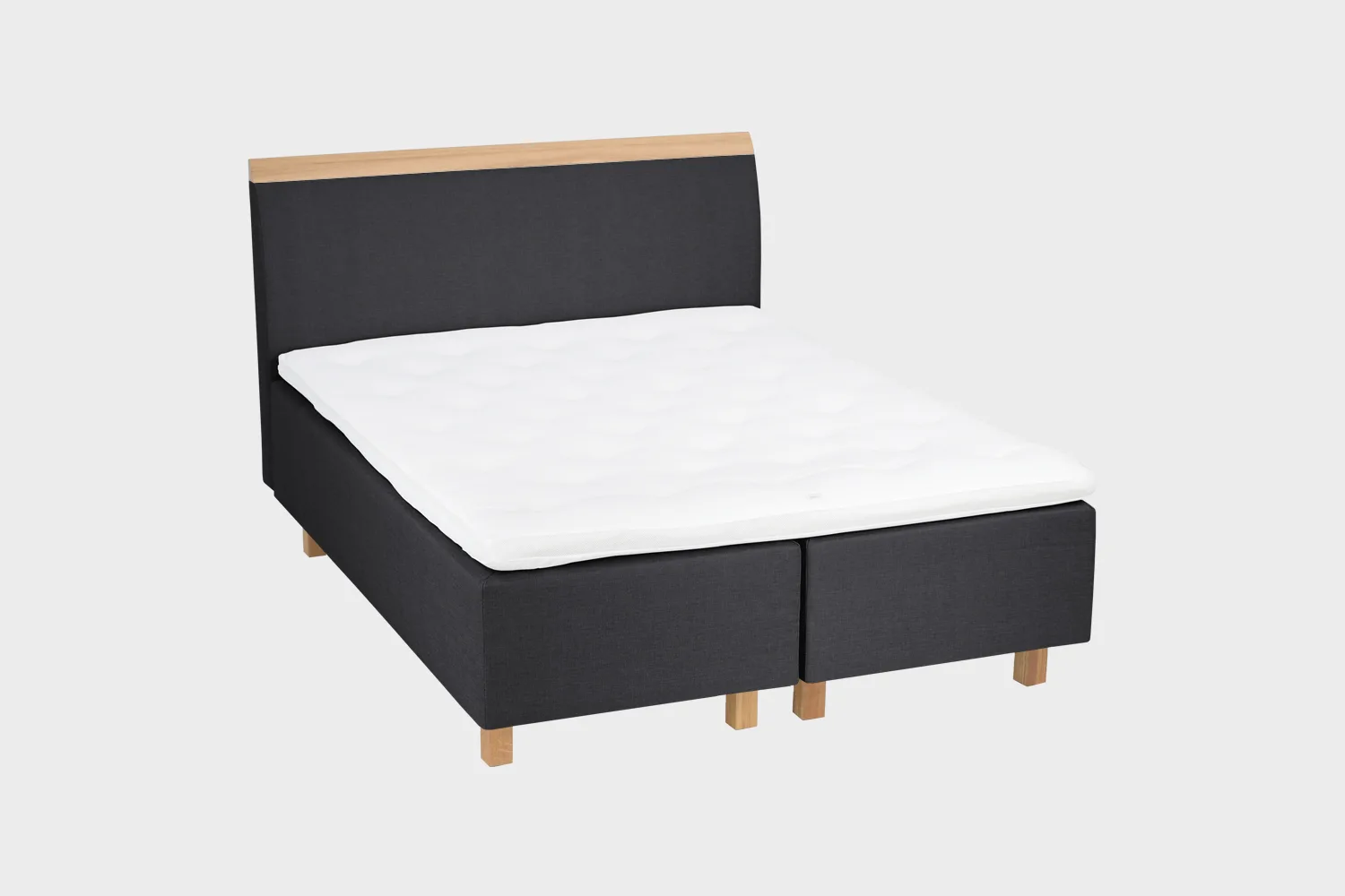 savoy-comfort-runkopatjasanky-180x200cm-das55-tammi-finsoffat Musta runkosänky 180x200 cm tammen värisillä jaloilla ja mustalla sängynpäädyllä, jossa tammen värinen puukoristelista yläosassa. Kuvattuna viistosti vaaleanharmaata taustaa vasten.