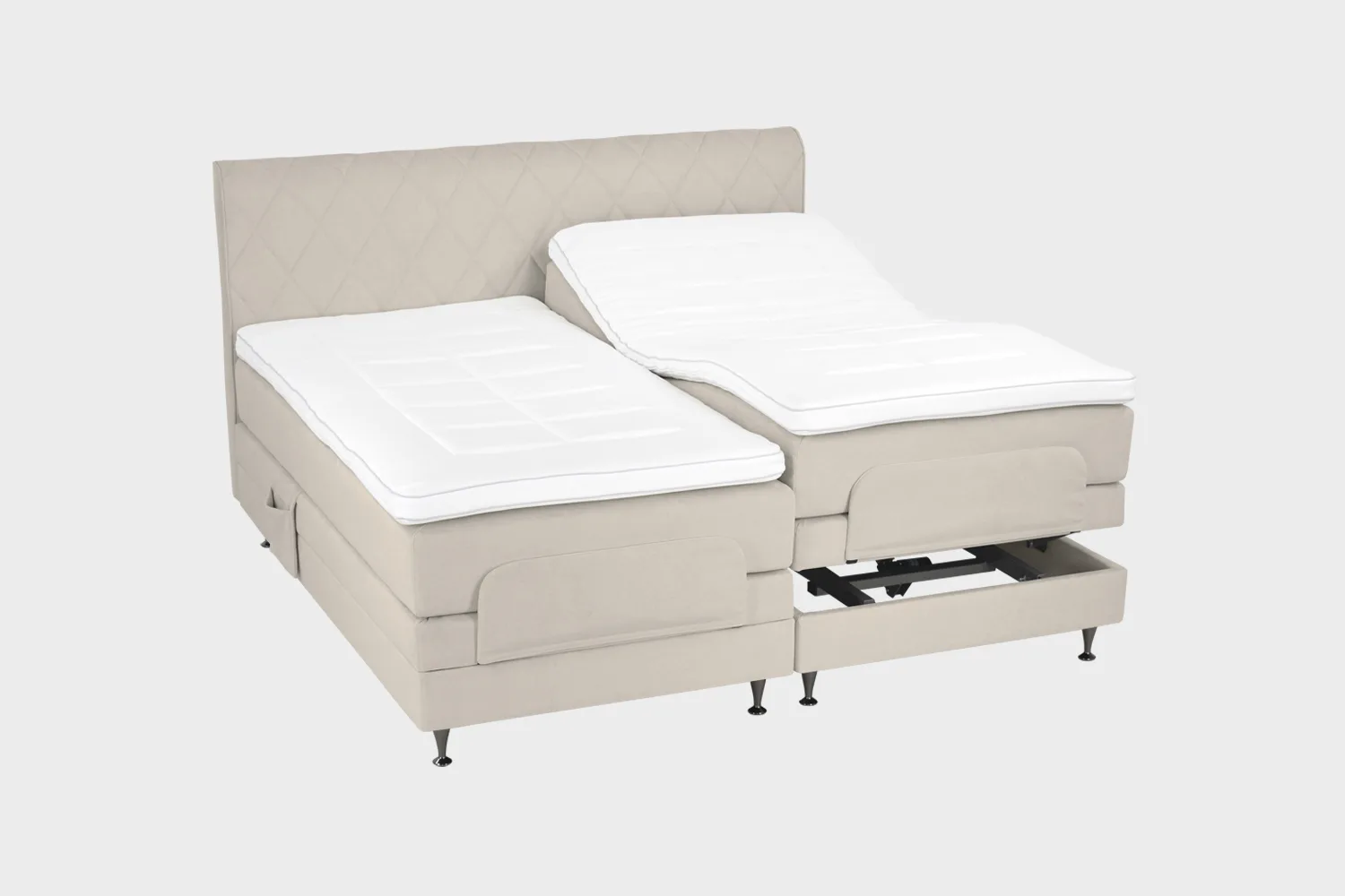 Vaalean beige moottorisänky 200x200 cm mustilla jaloilla sekä samanvärisellä sängynpäädyllä. Parisänky on kuvattuna viistosti toisen sänkypuoliskon päädyt aavistuksen koholla vaaleaa taustaa vasten.