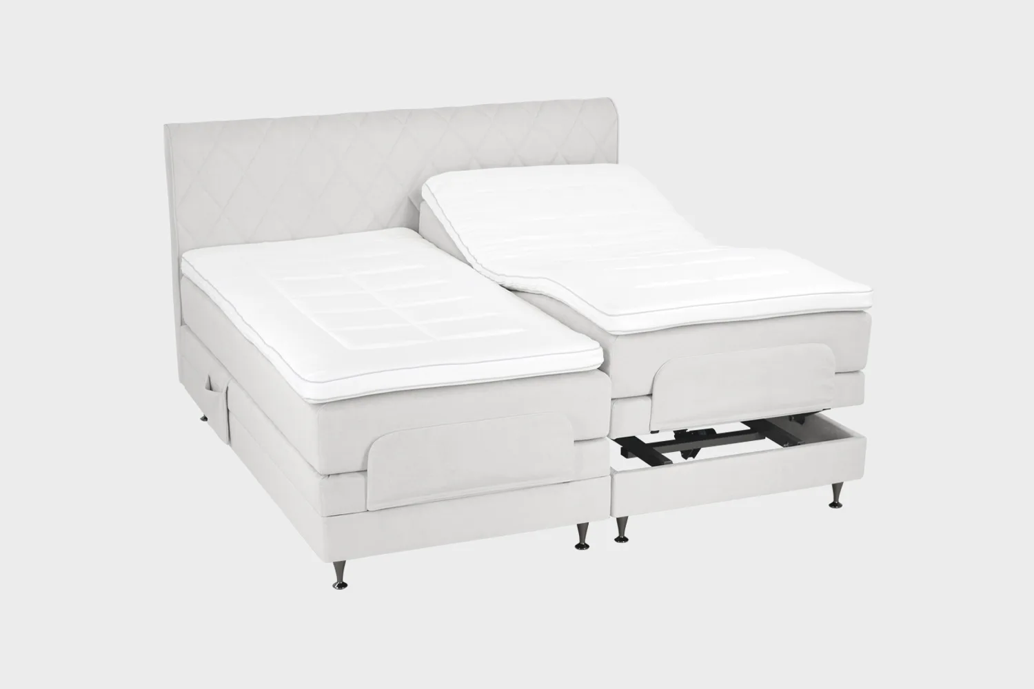 Vaalean harmaa moottorisänky 200x200 cm mustilla jaloilla sekä samanvärisellä sängynpäädyllä. Parisänky on kuvattuna viistosti toisen sänkypuoliskon päädyt aavistuksen koholla vaaleaa taustaa vasten.